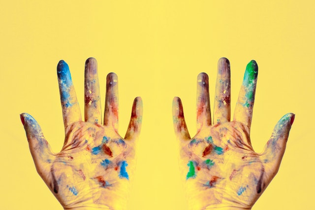 two hands stained with paint on yellow background