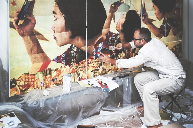 a man in white painting an abstract piece of a lady